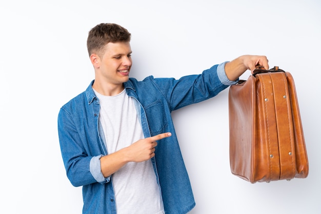 Hombre guapo joven sobre blanco sosteniendo un maletín vintage