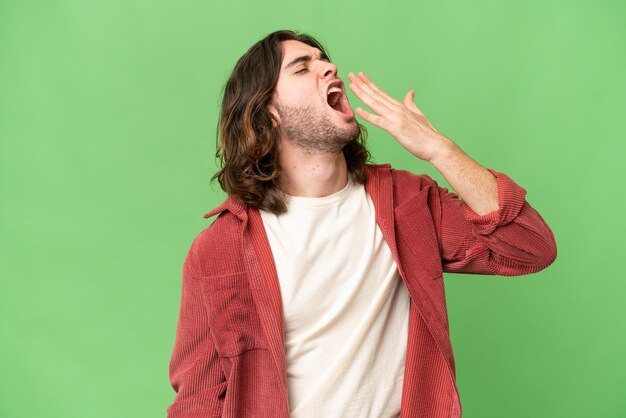 Hombre guapo joven sobre fondo aislado bostezando y cubriendo la boca abierta con la mano