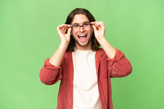 Hombre guapo joven sobre fondo aislado con gafas y sorprendido