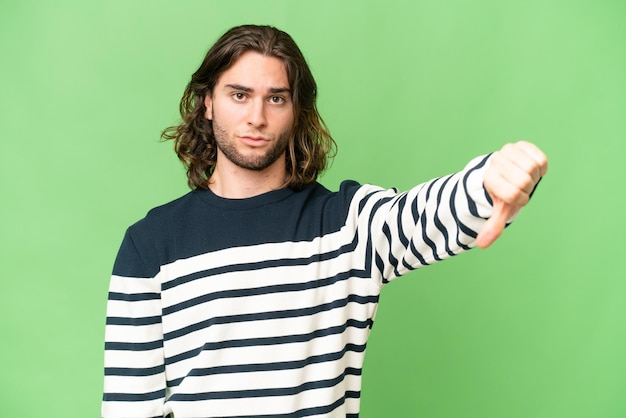 Hombre guapo joven sobre fondo aislado mostrando el pulgar hacia abajo con expresión negativa