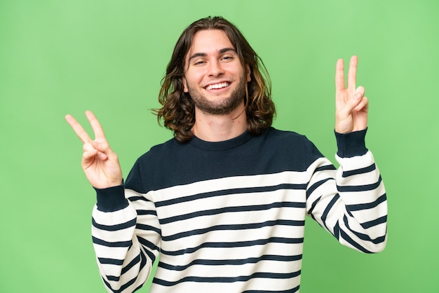 Hombre guapo joven sobre fondo aislado que muestra el signo de la victoria con ambas manos