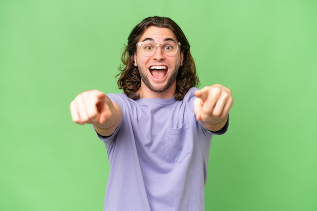 Hombre guapo joven sobre fondo aislado sorprendido y apuntando al frente