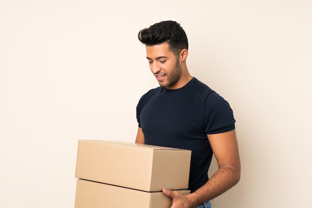 Hombre guapo joven sobre fondo aislado sosteniendo una caja para moverlo a otro sitio