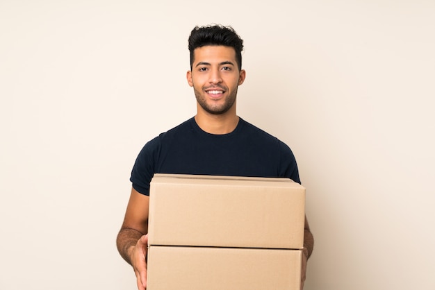 Foto hombre guapo joven sobre fondo aislado sosteniendo una caja para moverlo a otro sitio