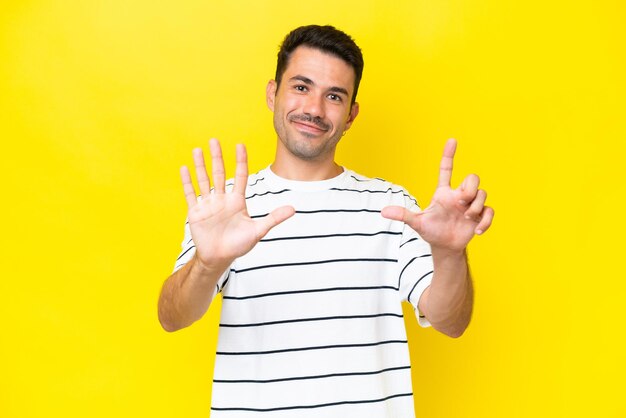 Hombre guapo joven sobre fondo amarillo aislado contando siete con los dedos