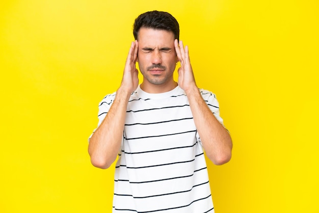 Hombre guapo joven sobre fondo amarillo aislado con dolor de cabeza