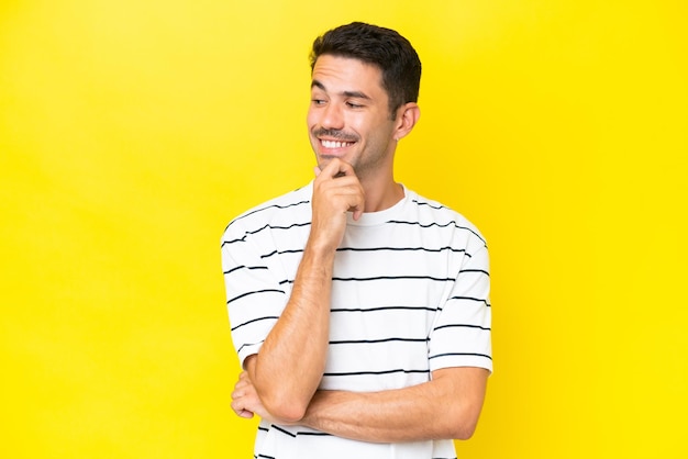 Hombre guapo joven sobre fondo amarillo aislado mirando hacia un lado y sonriendo
