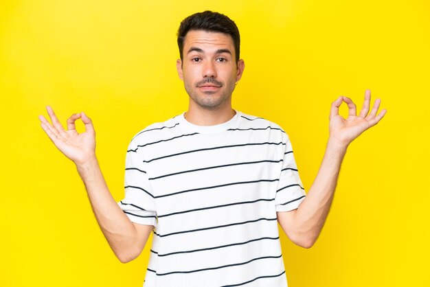 Hombre guapo joven sobre fondo amarillo aislado en pose zen