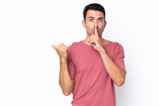 Hombre guapo joven sobre fondo blanco aislado apuntando hacia un lado y haciendo gesto de silencio