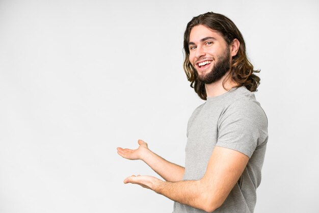 Hombre guapo joven sobre fondo blanco aislado extendiendo las manos a un lado para invitar a venir