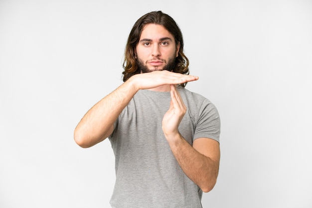 Hombre guapo joven sobre fondo blanco aislado haciendo gesto de tiempo de espera