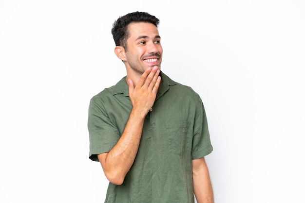 Hombre guapo joven sobre fondo blanco aislado mirando hacia arriba mientras sonríe