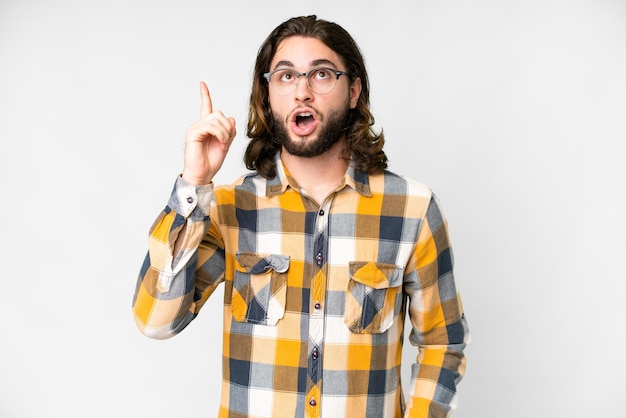 Hombre guapo joven sobre fondo blanco aislado pensando en una idea apuntando con el dedo hacia arriba