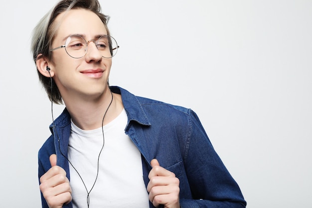 Hombre guapo joven sobre fondo de estudio blanco escuchando música en auriculares