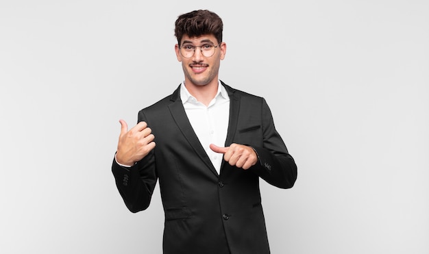 Hombre guapo joven sonriendo alegre y casualmente apuntando al espacio de la copia en el costado, sintiéndose feliz y satisfecho