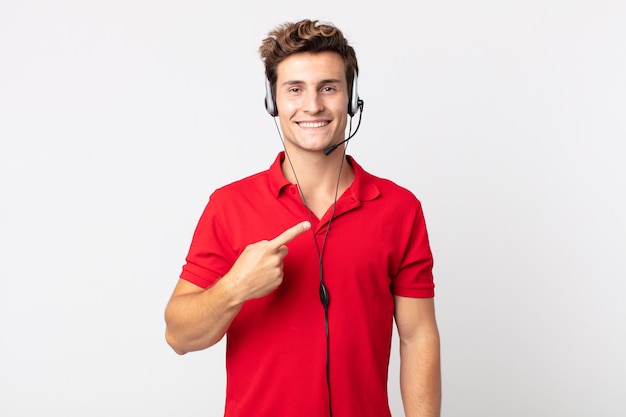 Hombre guapo joven sonriendo alegremente, sintiéndose feliz y apuntando hacia un lado. concepto de telemarketer