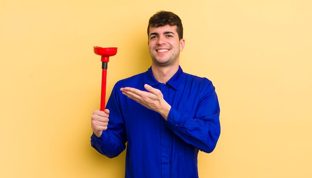 Hombre guapo joven sonriendo alegremente sintiéndose feliz y mostrando un concepto concepto de fontanero