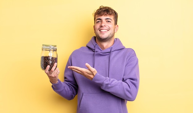 Hombre guapo joven sonriendo alegremente, sintiéndose feliz y mostrando un concepto. concepto de granos de cafe