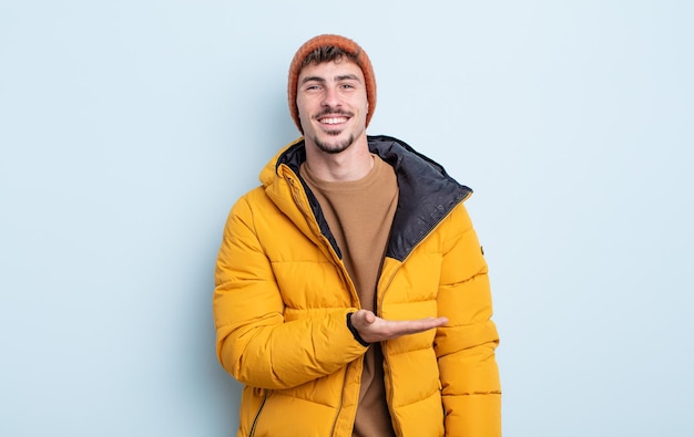 Hombre guapo joven sonriendo alegremente, sintiéndose feliz y mostrando un concepto. concepto de invierno