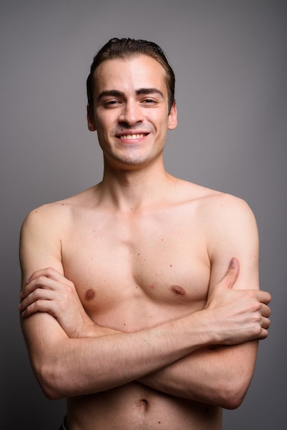 Hombre guapo joven sonriendo sin camisa con los brazos cruzados