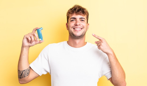 Hombre guapo joven sonriendo con confianza apuntando a su propia amplia sonrisa. concepto de asma