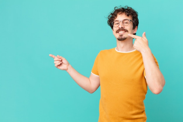 Hombre guapo joven sonriendo con confianza apuntando a su propia amplia sonrisa