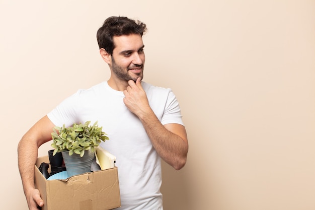 Hombre guapo joven sonriendo con una expresión feliz y segura con la mano en la barbilla