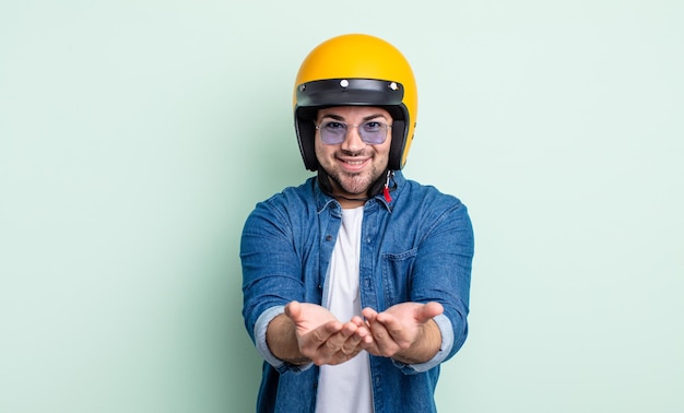 Hombre guapo joven sonriendo felizmente con amable y ofreciendo y mostrando un concepto. concepto de casco de moto