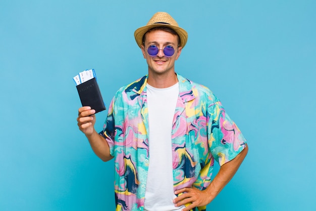 Hombre guapo joven sonriendo felizmente con una mano en la cadera y actitud confiada, positiva, orgullosa y amistosa