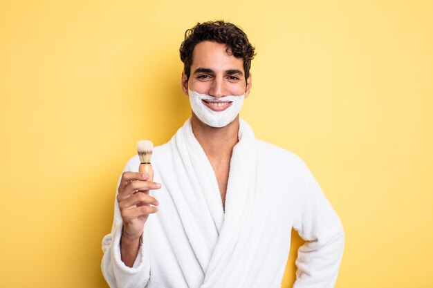 Hombre guapo joven sonriendo felizmente con una mano en la cadera y confiado. concepto de afeitado y espuma