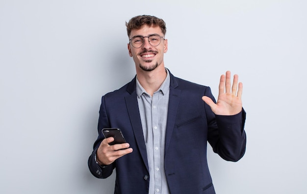 Hombre guapo joven sonriendo felizmente, saludando con la mano, dándote la bienvenida y saludándote. concepto de negocio