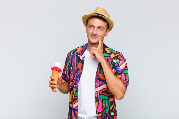 Hombre guapo joven sonriendo felizmente y soñando despierto o dudando, mirando hacia un lado