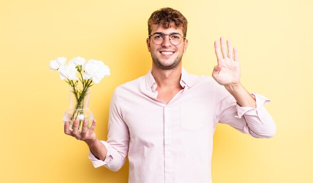 Hombre guapo joven sonriendo y luciendo amigable mostrando el concepto de flores número cuatro