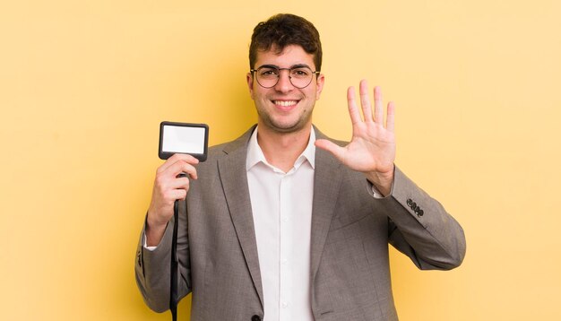 Hombre guapo joven sonriendo y luciendo amigable mostrando el concepto de pase vip número cinco