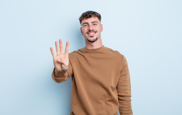 Hombre guapo joven sonriendo y luciendo amigable mostrando el número cuatro o cuarto con la mano hacia adelante contando hacia atrás