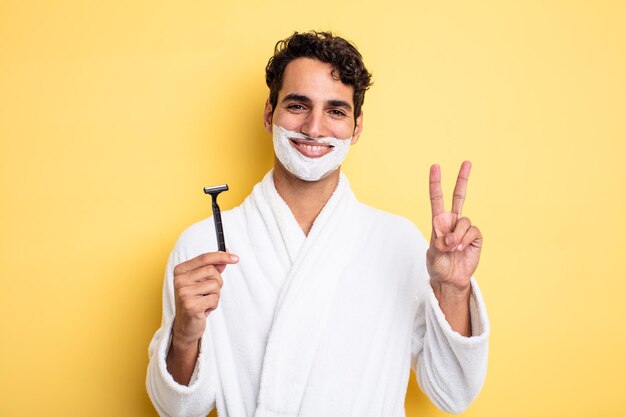 Hombre guapo joven sonriendo y luciendo feliz, gesticulando victoria o paz. concepto de afeitado y espuma