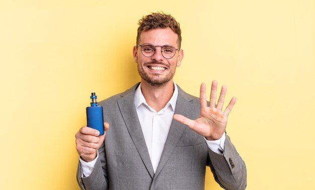 Hombre guapo joven sonriendo y mirando amigable, mostrando el número cinco. concepto de vaporizador