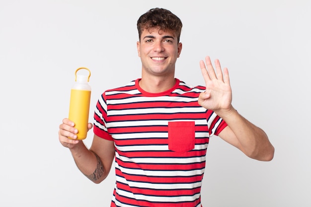 Hombre guapo joven sonriendo y mirando amigable, mostrando el número cuatro y sosteniendo un termo de café