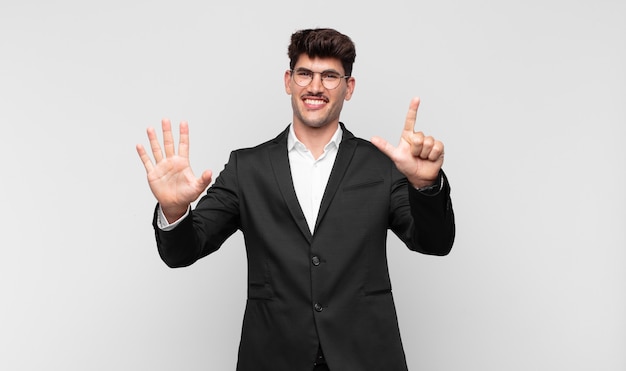 Hombre guapo joven sonriendo y mirando amigablemente, mostrando el número siete o séptimo con la mano hacia adelante, contando hacia atrás