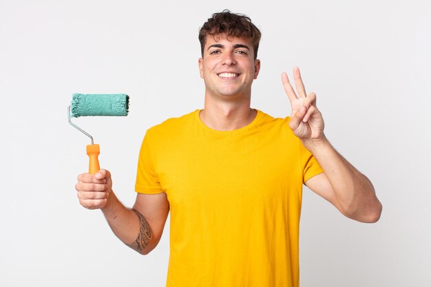 Hombre guapo joven sonriendo y mirando amistoso, mostrando el número dos. concepto de casa de pintura