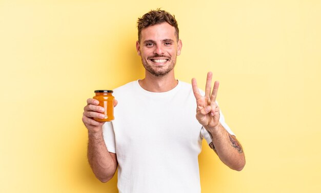 Hombre guapo joven sonriendo y mirando amistoso, mostrando el número tres. concepto de gelatina de durazno