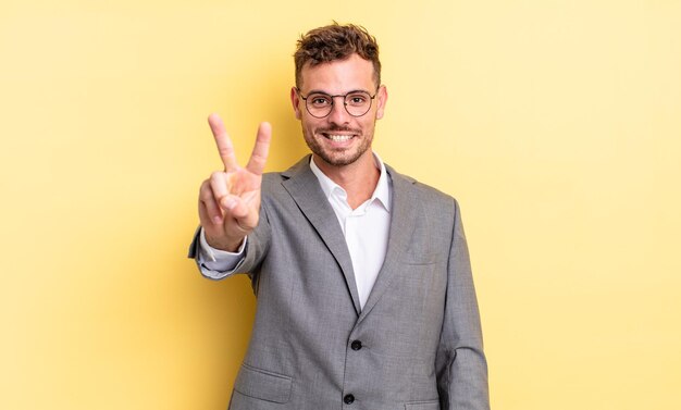 Hombre guapo joven sonriendo y mirando feliz, gesticulando victoria o paz. concepto de negocio