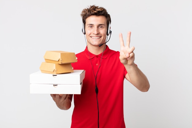 Hombre guapo joven sonriendo y mirando feliz, gesticulando victoria o paz. llevar concepto de comida rápida