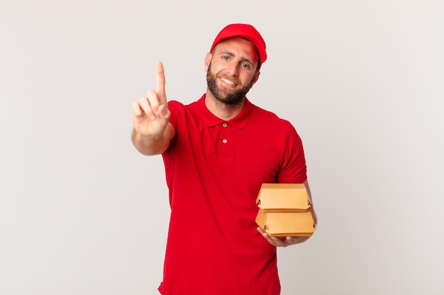 Hombre guapo joven sonriendo con orgullo y confianza haciendo hamburguesa número uno entregando concepto