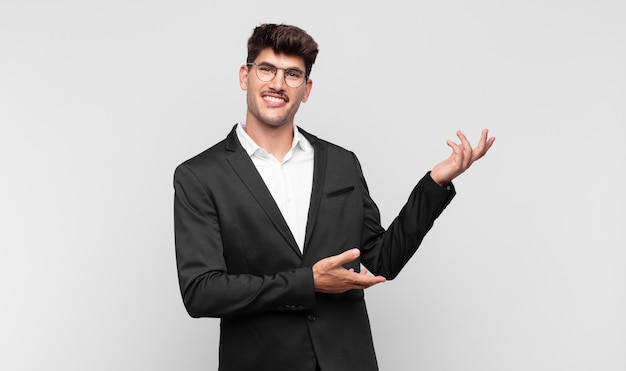 Hombre guapo joven sonriendo con orgullo y confianza, sintiéndose feliz y satisfecho y mostrando un concepto en el espacio de la copia