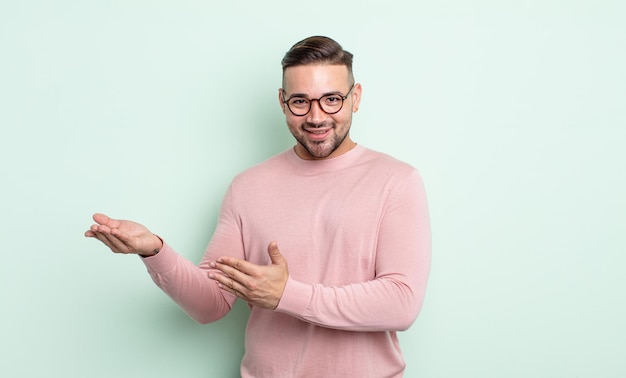 Hombre guapo joven sonriendo con orgullo y confianza, sintiéndose feliz y satisfecho y mostrando un concepto en el espacio de la copia