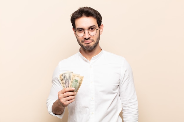 Hombre guapo joven sonriendo positivamente y con confianza, luciendo satisfecho, amigable y feliz