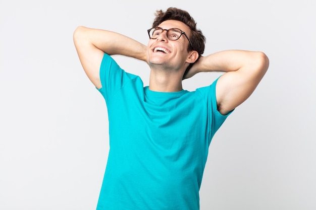 Foto hombre guapo joven sonriendo y sintiéndose relajado, satisfecho y despreocupado, riendo positivamente y escalofriante