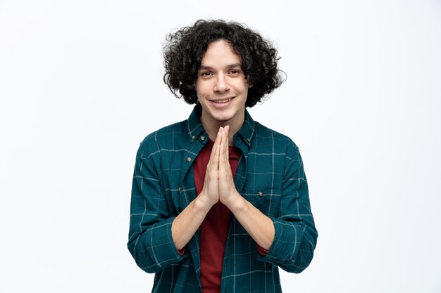 Hombre guapo joven sonriente mirando a la cámara haciendo gesto namaste aislado sobre fondo blanco.