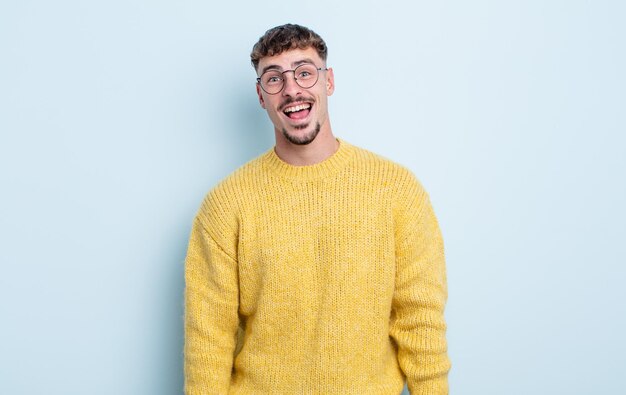 Hombre guapo joven con una sonrisa grande, amigable y despreocupada, con aspecto positivo, relajado y feliz, escalofriante.